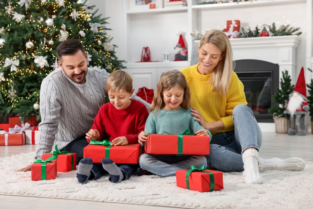 Des enfants ouvrent leurs cadeaux de Noël à la maison avec leurs parents