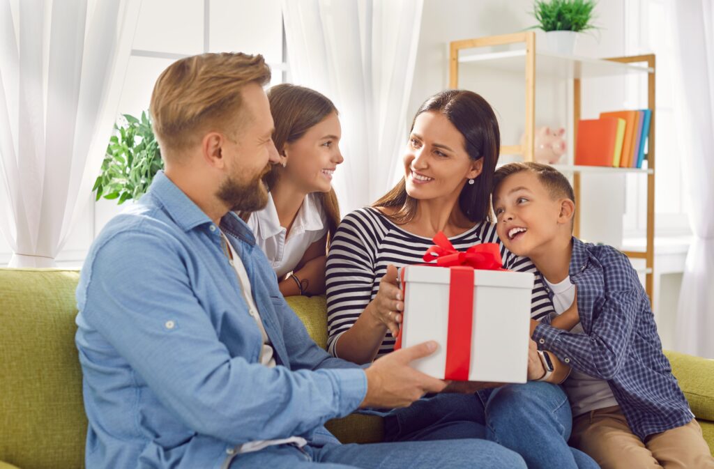 Une femme reçoit une grande boîte de cadeaux de son mari et de ses enfants à l'occasion de noël. 