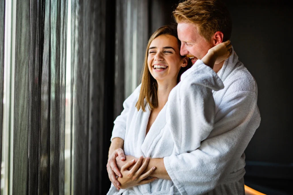 Un couple souriant qui profite de la saint-valentin pour passer un momment de détente dans un spa.