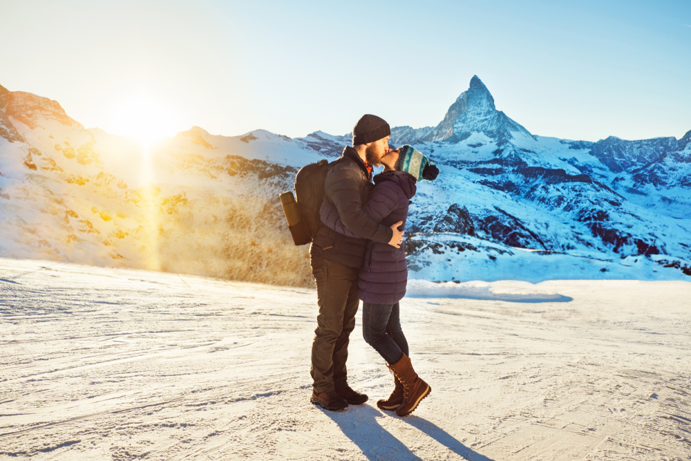 Un couple en randonnée dans les Alpes suisses, profitant d'une belle vue sur le Cervin au coucher du soleil, s'embrassant. Vacances romantiques en plein air dans la nature pour la Saint-Valentin.