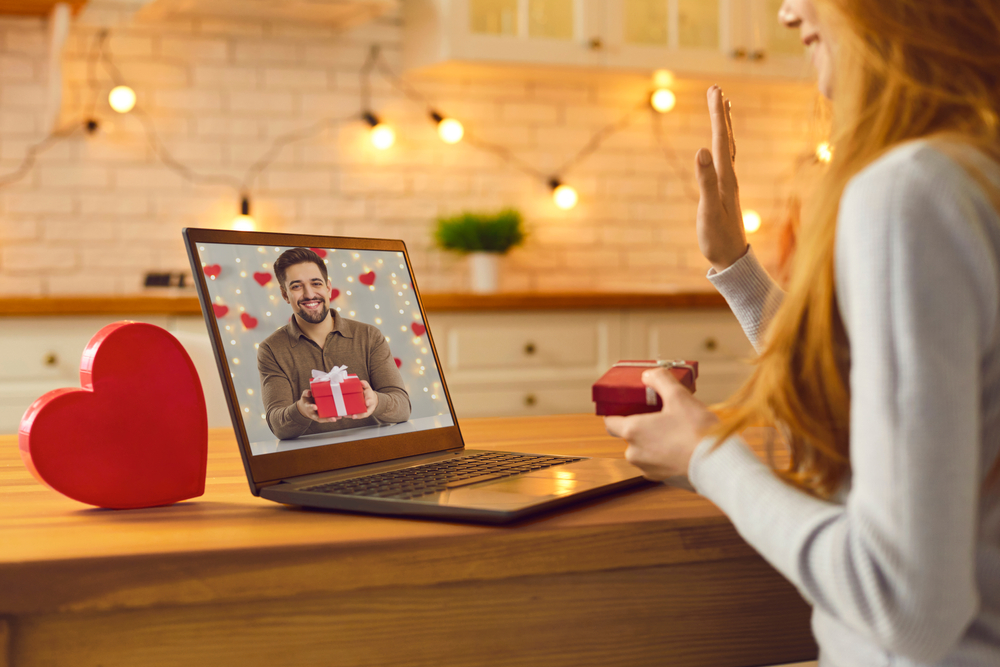 Un couple en relation à distance et rendez-vous virtuel sur un ordinateur. Un jeune couple amoureux s'appelle en vidéo pendant la saint-valentin et montre les cadeaux qu'il a préparés pour la Saint-Valentin.